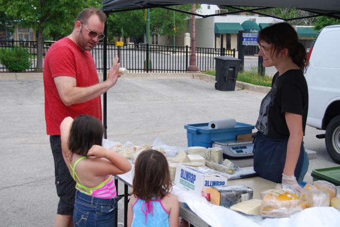 Alex Congi (left) shows customers her selection of farm-fresh cheese at the Chicago Farmers Market in Beverly.